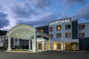 Un hotel Courtyard by Marriott con entrada cubierta, varios pisos y fachada bien iluminada.