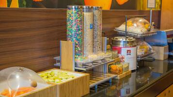 A breakfast buffet with various food options including cereal, oatmeal, and fruits.
