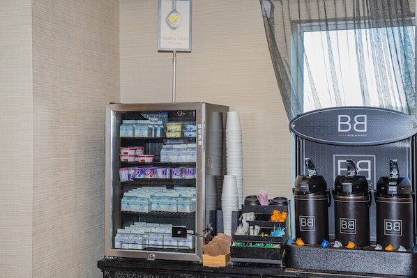 Un distributeur automatique rempli de divers produits alimentaires et boissons, une machine à café et un panneau indiquant les options saines.