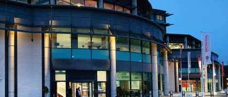 A modern building with a curved facade, large windows, and a sign for 'Live Sport Bar'.