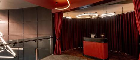 A modern interior with a reception desk, red curtains, and a staircase with metal railings.