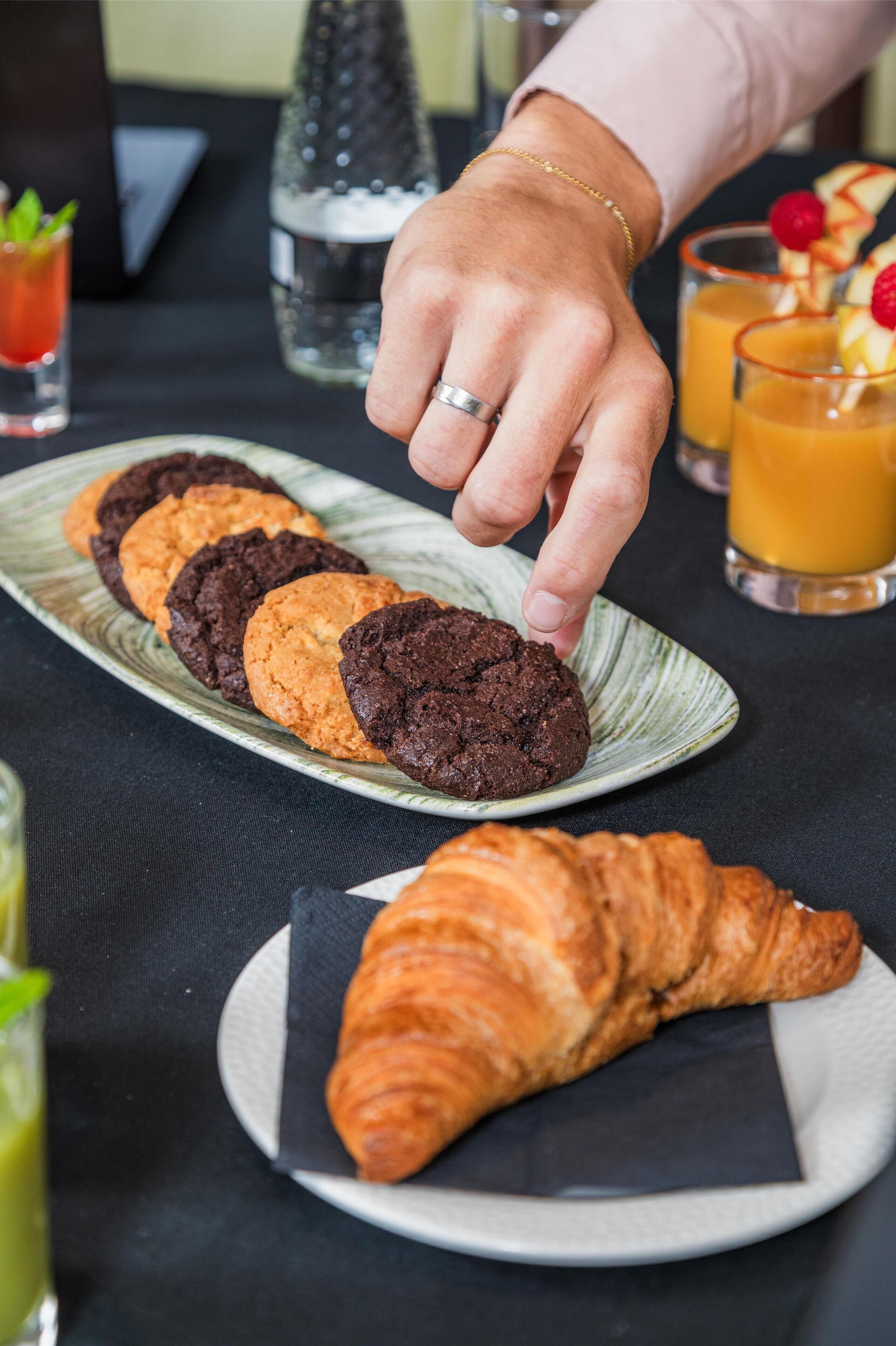 A plate with cookies and a croissant on a table.