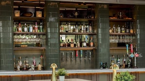 A bar area with multiple shelves of liquor bottles, a variety of bar tools, and seating with a modern design. - Radisson RED London Twickenham (Twickenham)