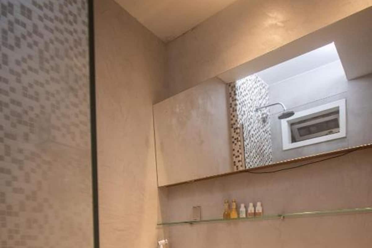 Casa de banho moderna com sanita, chuveiro e zona de duche com divisória de vidro.