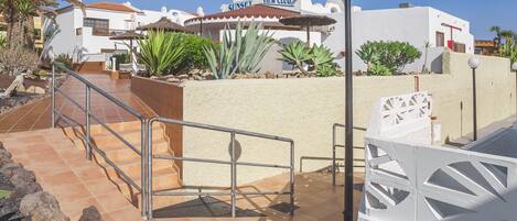 Un resort con un edificio blanco, una terraza con barandilla y una palmera.