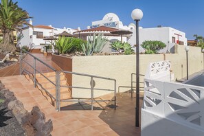 A resort with a white building, a terrace with a railing, and a palm tree. - Sunset View Club (San Miguel de Abona)