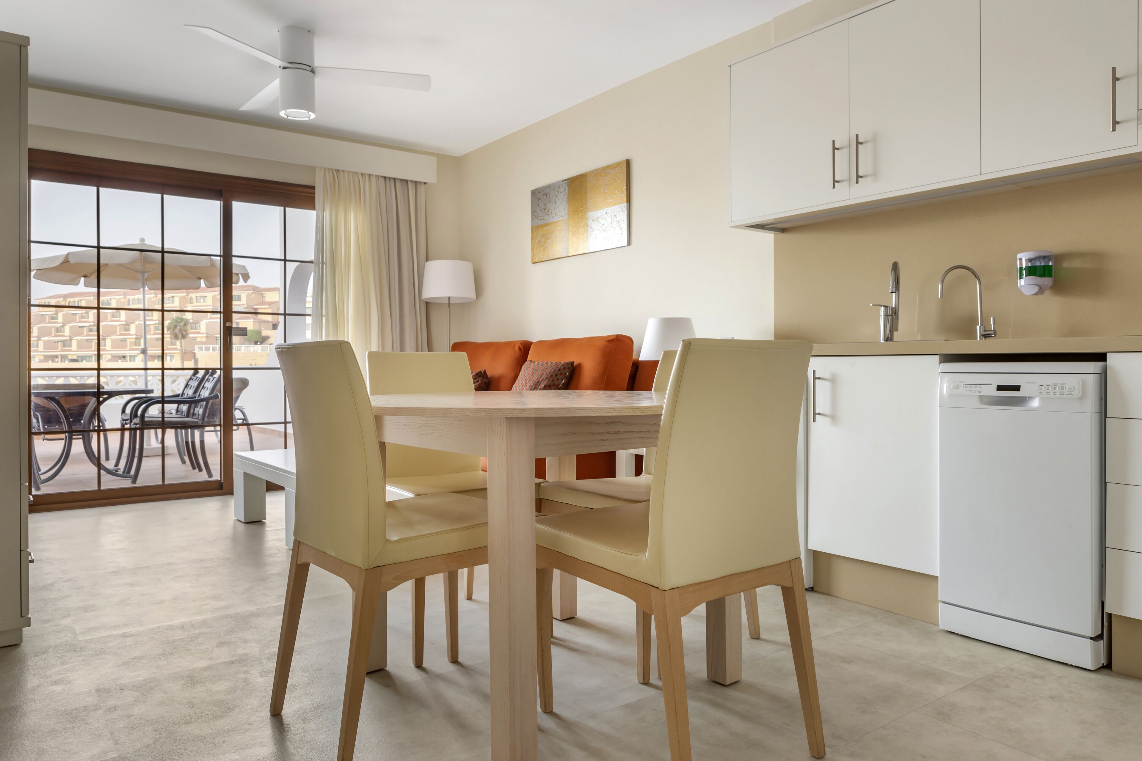 Una cocina moderna con comedor, lavavajillas y vistas amplias a través de ventanales.