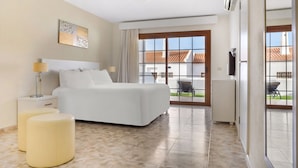 A hotel room with a bed, bedside tables, a large window, and a view of the outside.