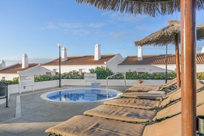 A pool area with lounge chairs, a sign, and buildings with red-tiled roofs. - Sunset View Club (San Miguel de Abona)