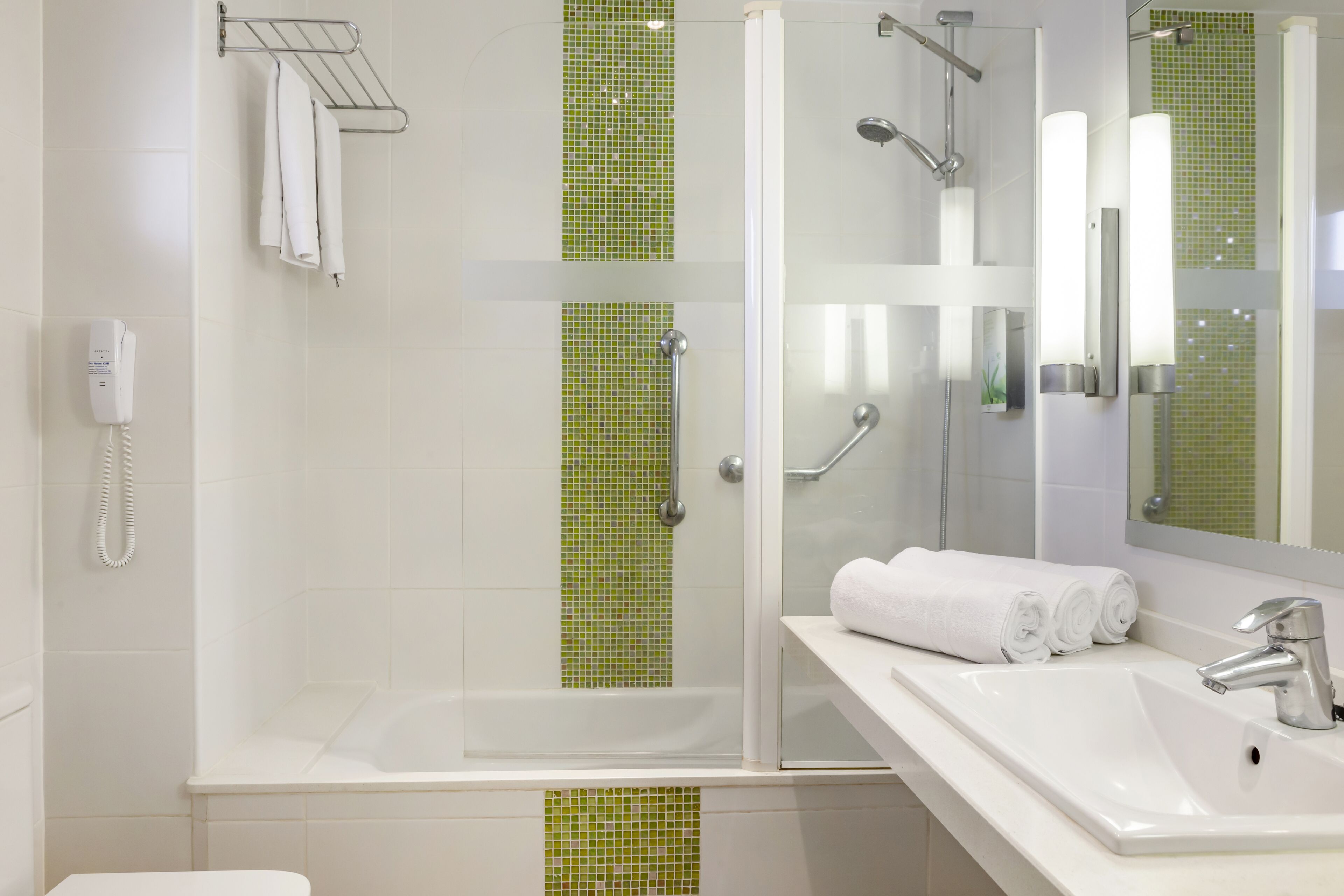 A modern bathroom with a glass-enclosed shower, a white sink, and a mirror.