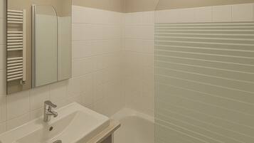 A bathroom with a sink, mirror, and a glass-enclosed shower.