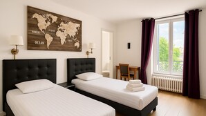 A hotel room with two beds, a world map on the wall, a desk, and a window with curtains. - L'Hôtel du Cirque (Troyes)