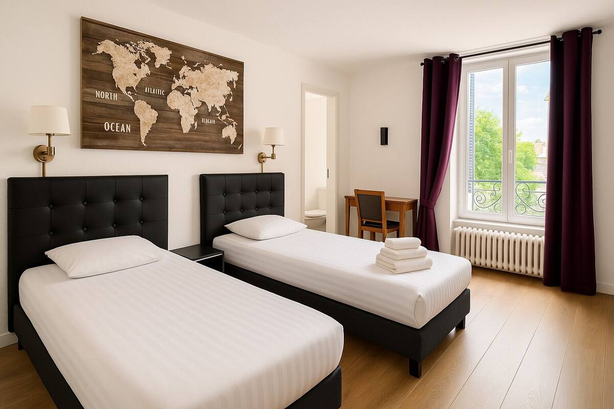 Hotellihuone, jossa on kaksi sänkyä, maailmankartta seinällä, työpöytä ja ikkuna, jossa on verhot.