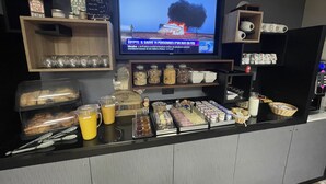 A breakfast bar with various food items and a television displaying a news channel. - L'Hôtel du Cirque (Troyes)