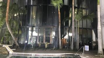 Vue nocturne d’un bâtiment doté d’une piscine, de palmiers et d’un espace de détente extérieur.