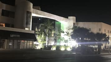Un edificio moderno con fachada curva, ventanas amplias y entrada iluminada en verde.