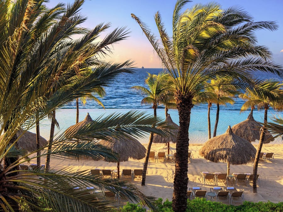 Praia particular, areia branca, espreguiçadeiras, guarda-sóis