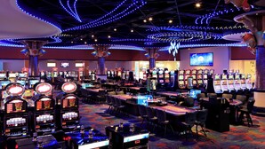 A casino with multiple gaming tables and slot machines, illuminated by blue ceiling lights. - Renaissance Wind Creek Curacao Resort (Willemstad)