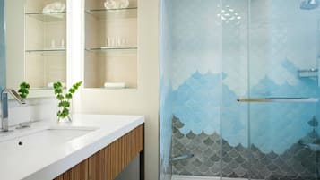 A modern bathroom with a glass shower enclosure, a white sink, and a wooden vanity.