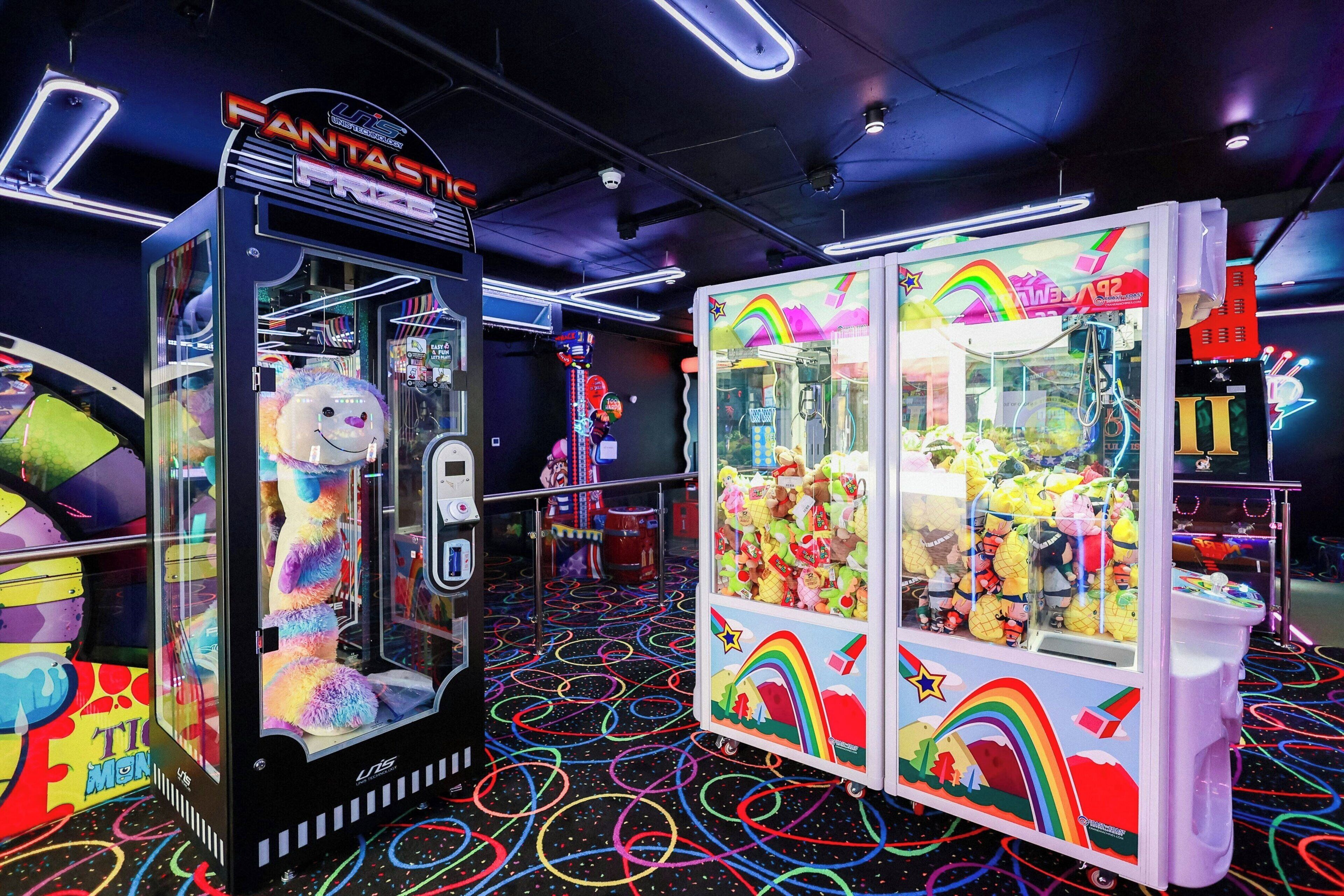 Máquina de garra en una sala recreativa con diseños coloridos y peluches en su interior.