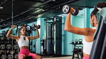 Un gimnasio con equipo de ejercicio y una persona levantando pesas.