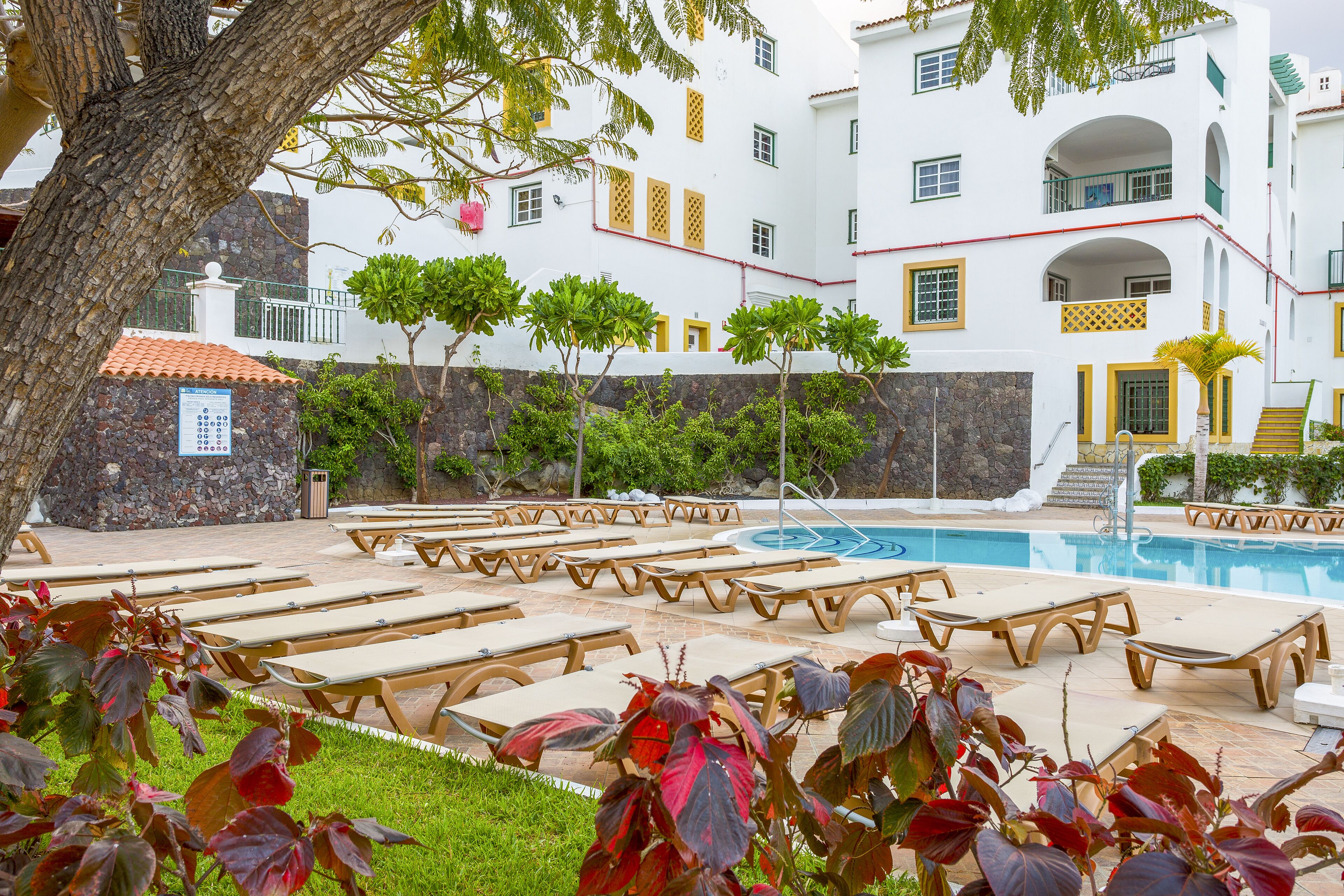 Un espace piscine avec des chaises longues et une piscine.
