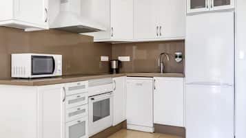 A modern kitchen with white cabinetry, a microwave, oven, dishwasher, and a refrigerator.