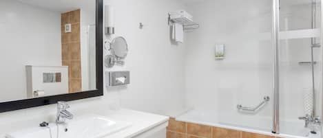 A modern bathroom with a white sink, a large mirror, a glass-enclosed shower, and a towel rack.