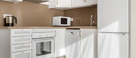 Une cuisine moderne avec des meubles blancs, un four à micro-ondes, un lave-vaisselle et un four traditionnel.