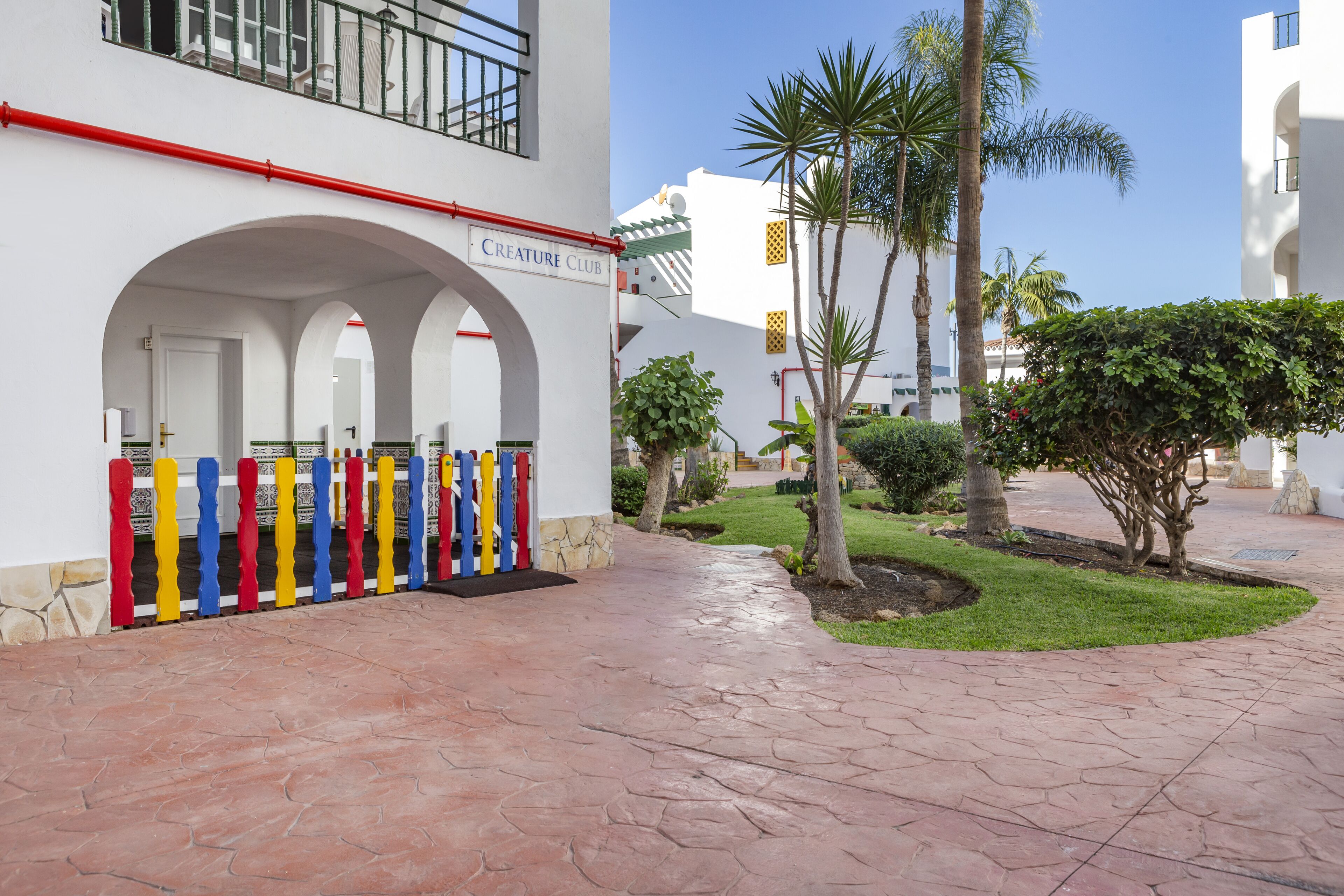 A building with a sign reading "CREATURE CLUB" and a colorful fence.