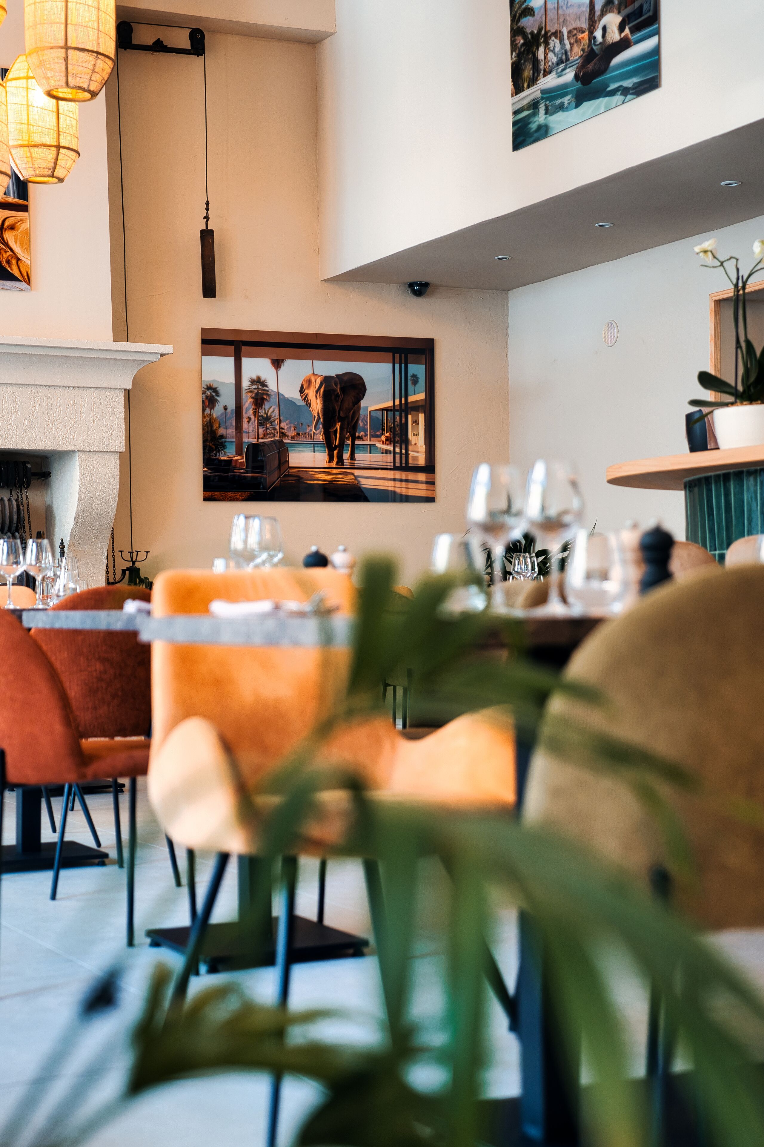 A dining area with a table set for two, a hanging light fixture, and a framed picture on the wall.
