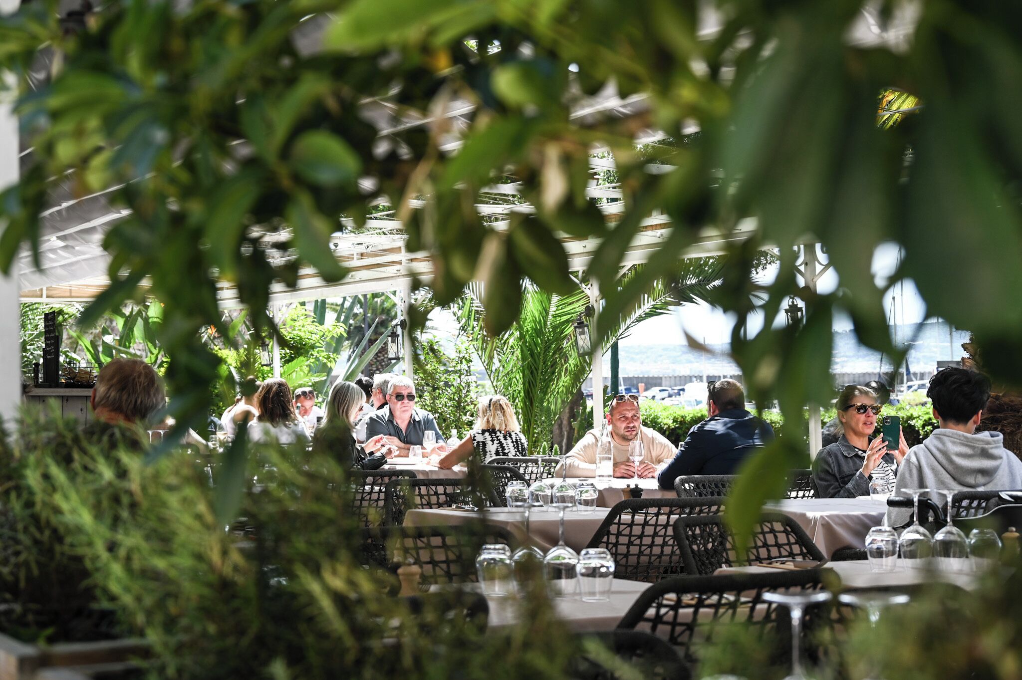 Un espace extérieur aménagé pour les repas, avec des tables et des chaises, entouré de verdure.