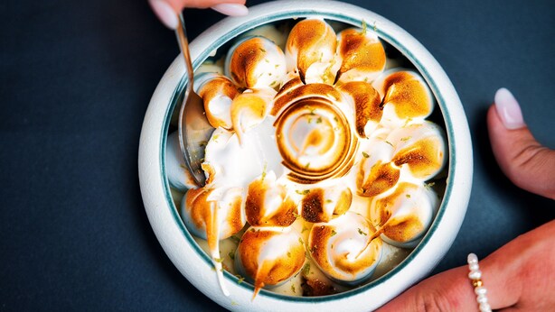 A bowl of food with a decorative swirl on top, held by a person.