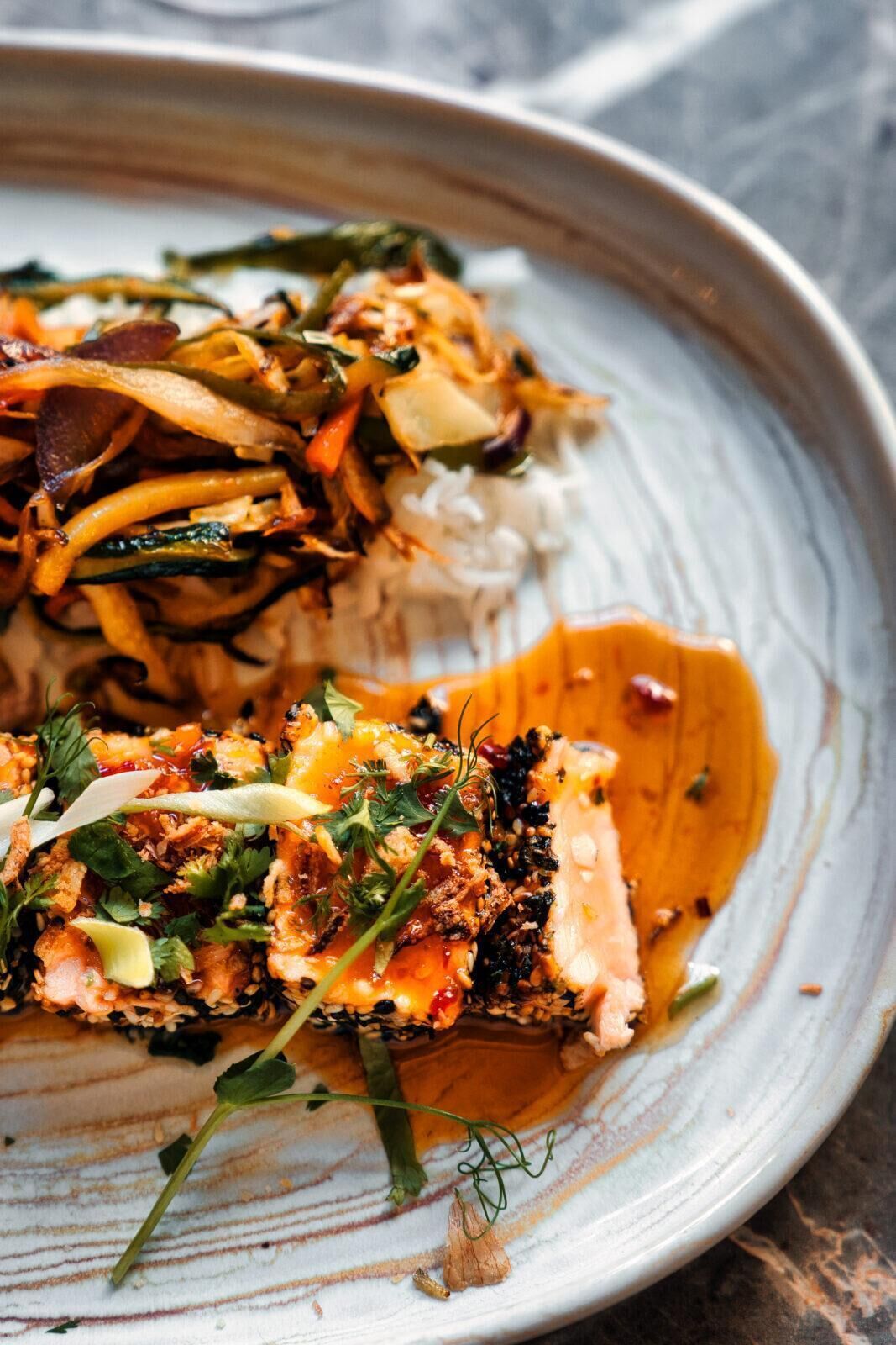 A plate of food with various vegetables and a piece of salmon.