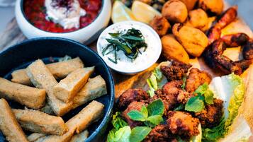 Variedad de alimentos fritos, como pollo frito, papas fritas y churros, acompañados de salsas y guarniciones.