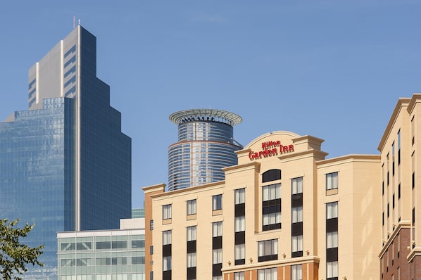 A hotel with a modern glass facade, a cylindrical tower, and a classic building with a sign. - Hilton Garden Inn Minneapolis Downtown (Minneapolis)