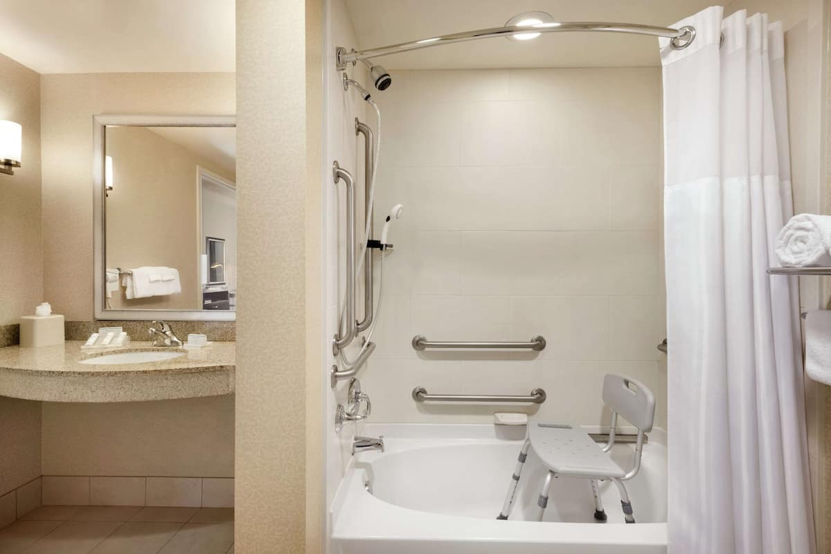 Un baño moderno con bañera, ducha y barras de apoyo.