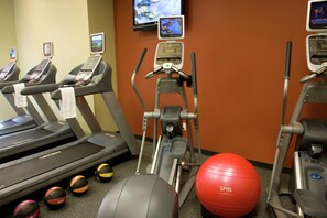 Academia com esteiras, elípticos e bolas de exercício.