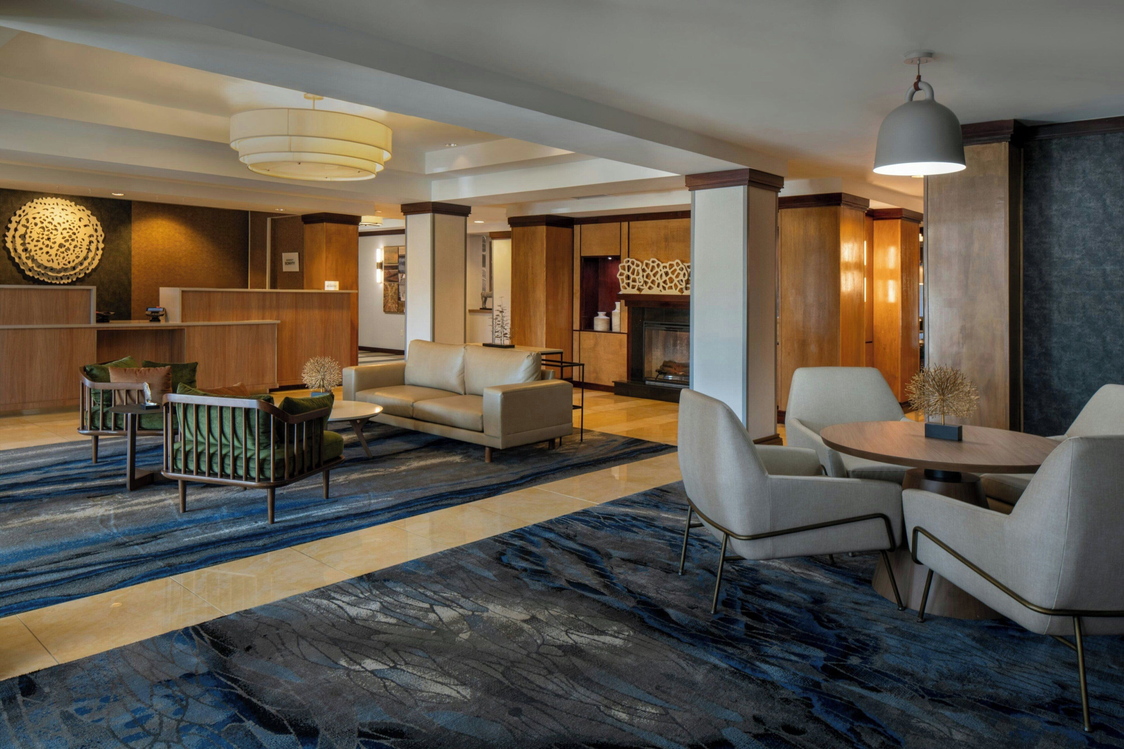 A hotel lobby with a reception desk, seating area, and a fireplace.