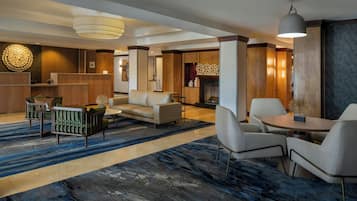 A hotel lobby with a reception desk, seating area, and a fireplace.