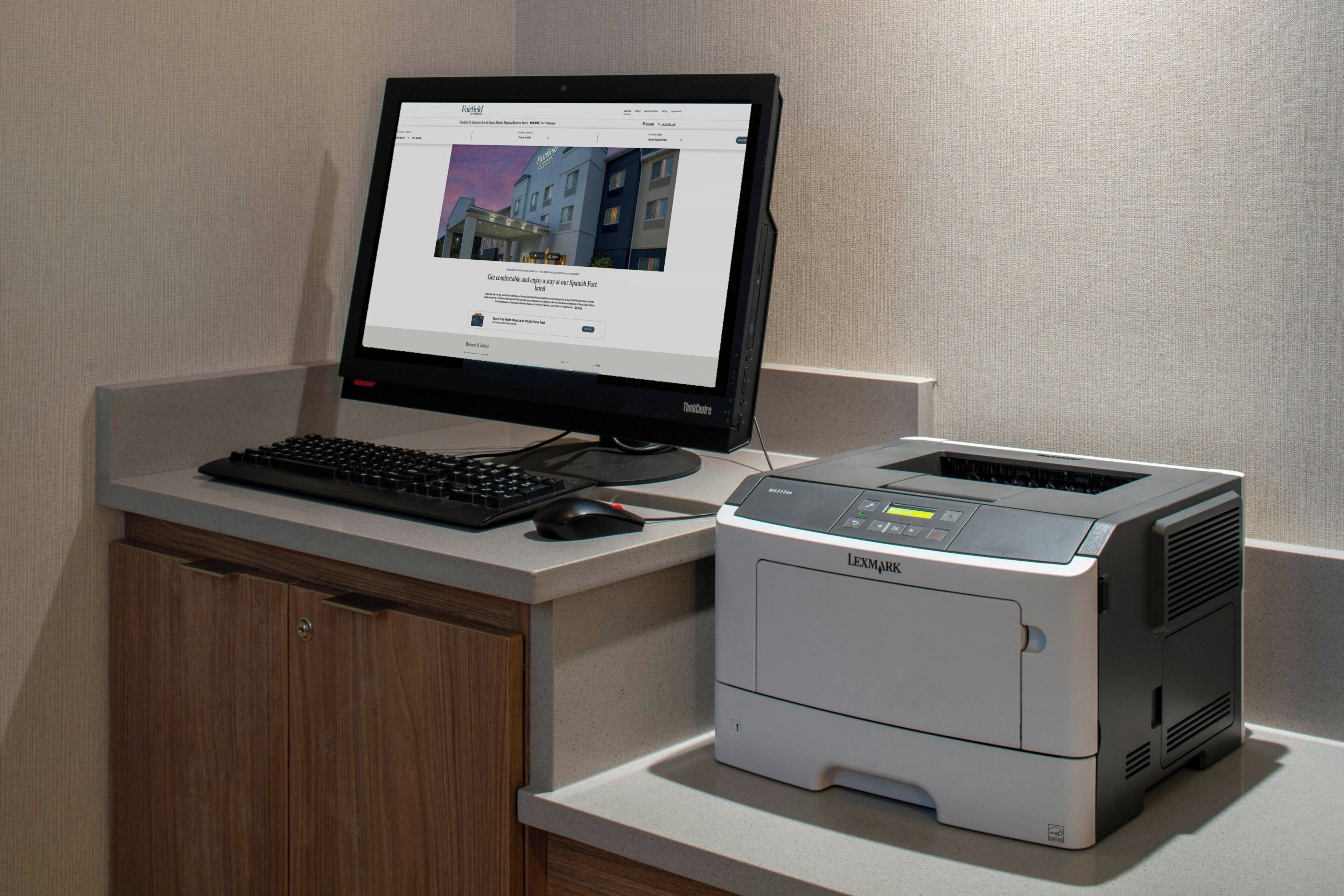 Työpöydällä on pöytätietokone, jossa on näyttö, näppäimistö ja hiiri, sekä Lexmark-merkkinen tulostin.