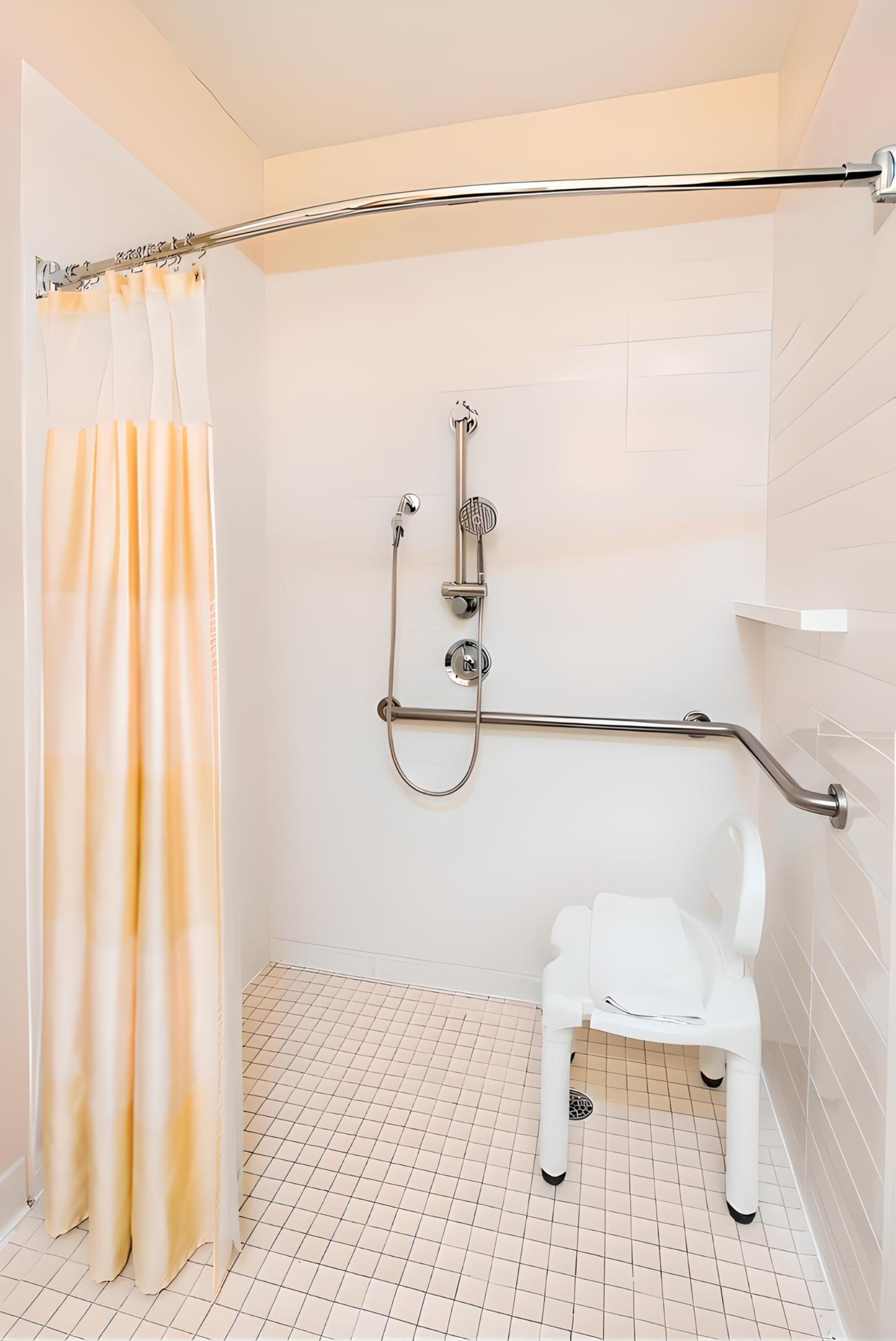 A bathroom with a shower, grab bar, and a white chair.