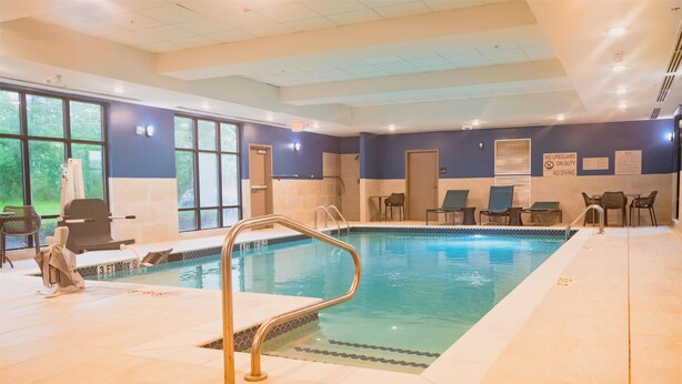 An indoor swimming pool with a lifeguard station, lounge chairs, and a sign indicating no lifeguard on duty. - Hampton Inn Gonzales (Gonzales)