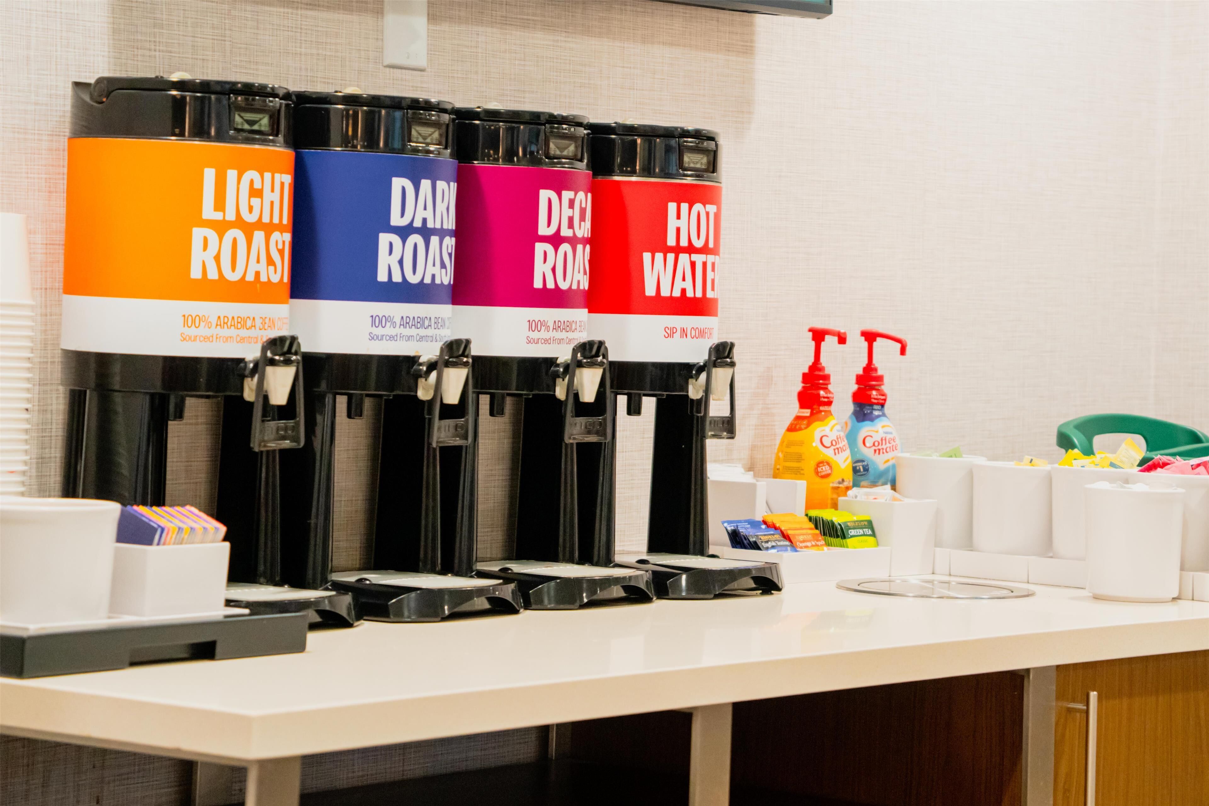 A coffee station with four dispensers labeled Light Roast, Dark Roast, Decaf Roast, and Hot Water.