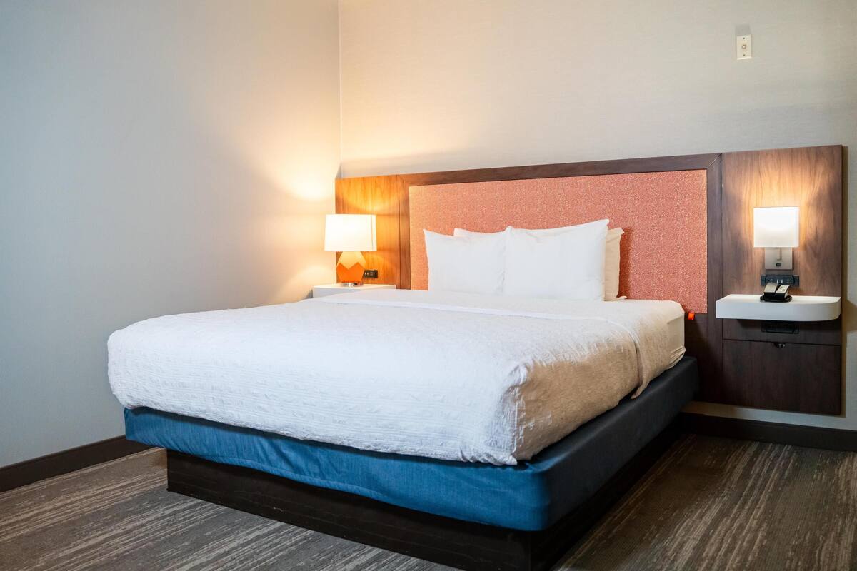 A hotel room with a bed, two bedside tables, and a nightstand.