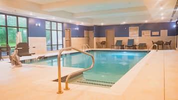 An indoor swimming pool with a lifeguard station, lounge chairs, and a sign indicating no lifeguard on duty.