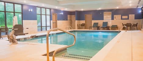 Una piscina interior con una estación de socorrista, sillas de descanso y un cartel que indica que no hay salvavidas de servicio.