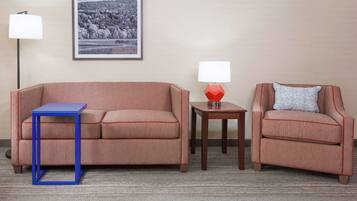 A room with a sofa, a chair, a small table, and a lamp.