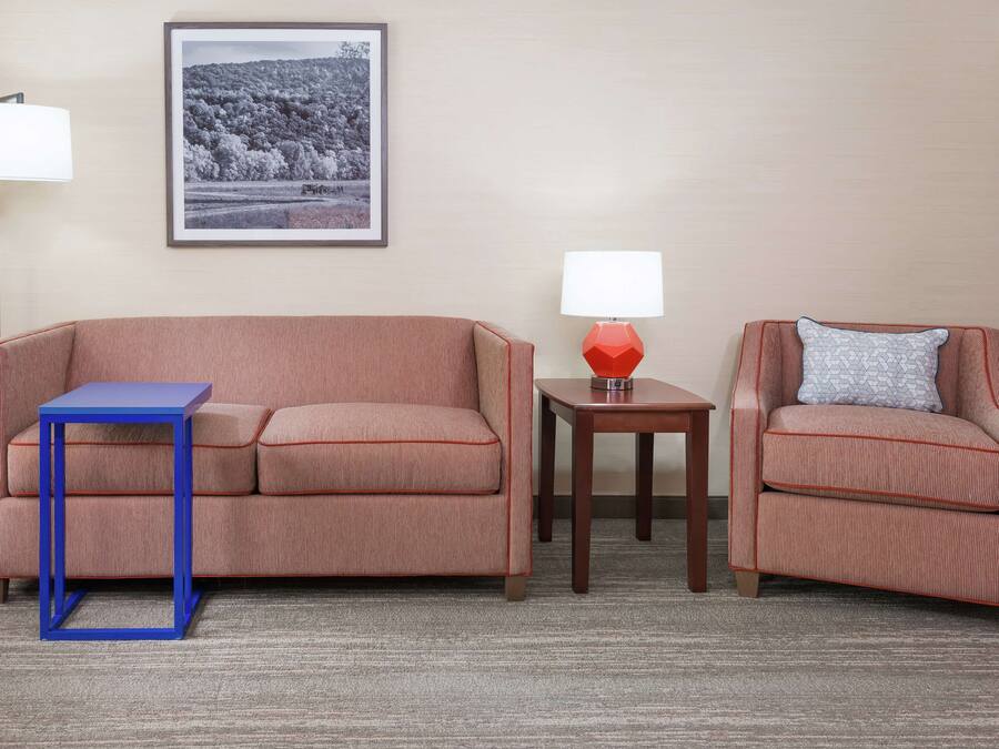 A room with a sofa, a chair, a small table, and a lamp.