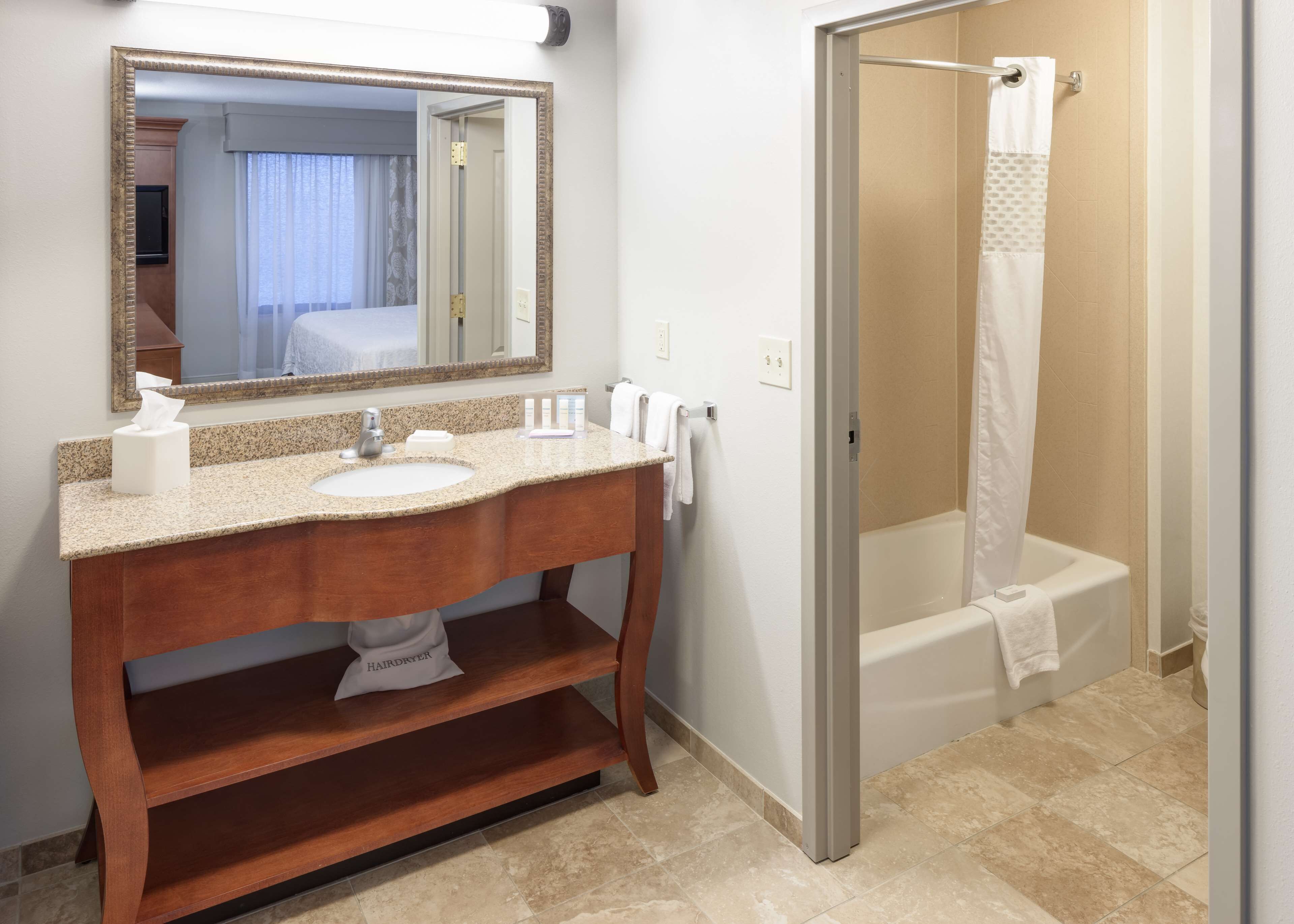 A bathroom with a sink, mirror, towel rack, and shower area.